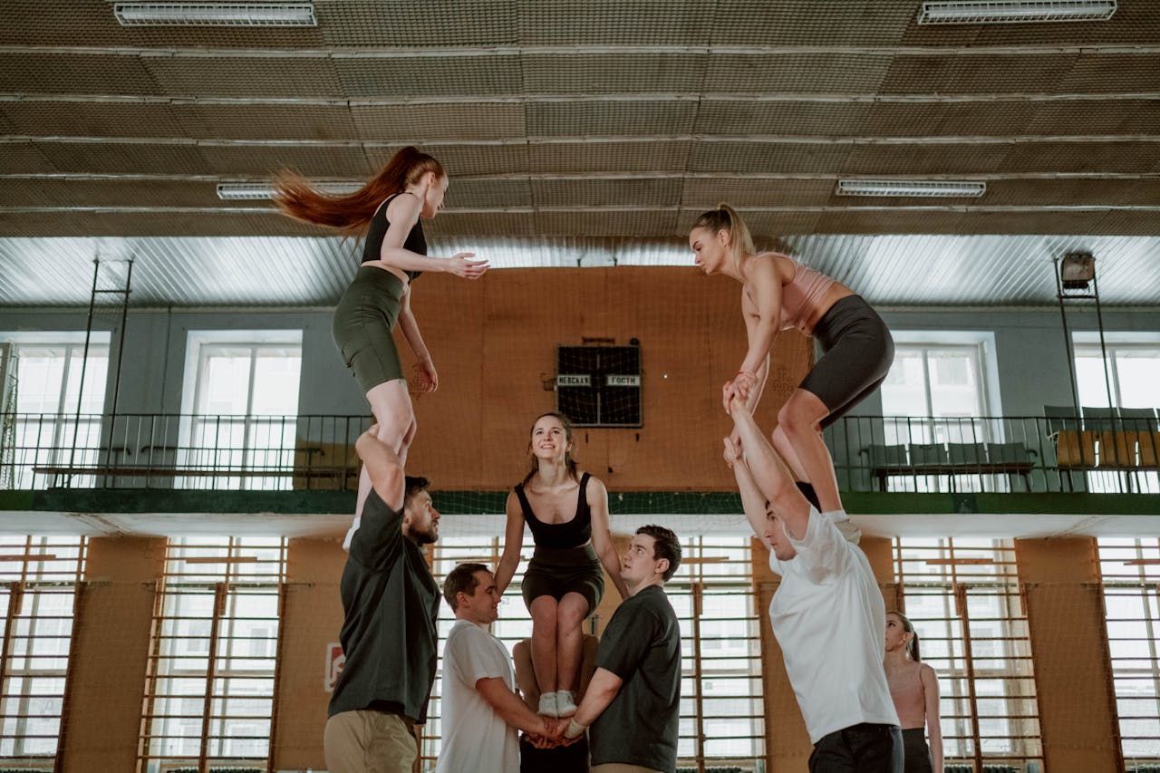 Group performing acrobatics in a gym setting, showcasing teamwork and balance skills.